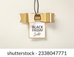 Black friday sale tag with gold bow on beige background