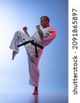 Small photo of Full-length portrait of young caucasioan sportsman practising martial art of Karate, judo, taekwondo isolated on gradient white blue background. Concept of martial art, combat sport, energy, fit, ad