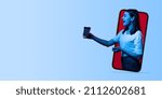 Small photo of Creative collage. Young cheerful girl sticking out phone screen with coffee cup isolated over blue background. Concept of online communic ation, business cooperation, teleworking and ad
