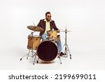 Small photo of Portrait of stylish brutal man in jacket and sunglasses playing drums isolated over white background. Concept of live music, performance, retro style, creativity, artistic lifestyle