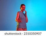 Small photo of Refusal, antipathy, dislike. Annoyed young girl with grimacing face and disgusted gestures over blue background in neon light. Concept of human emotion, self expression, mood, ad