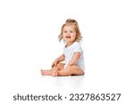 Small photo of Beautiful, happy, smiling child. Little baby girl, toddler sitting on floor with joy and fun against white studio background. Concept of childhood, motherhood, care, life, birth. Copy space for ad
