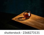 Small photo of Top view of glass of whiskey, rum, brandy or bourbon standing on wooden table over dark background. Concept of alcohol, strong spirits, drinks, liquid, nightlife, restaurant, club, pub. Ad