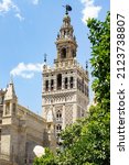 Small photo of Giralda Tower against a clear blue sky with white clouds.