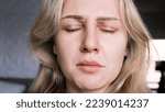 Small photo of Portrait of crying grieving woman of 30 years. Grimace of sadness with tears in her eyes and crooked chin of blonde woman with closed eyes. Emotional swing, unstable psyche, mental problems