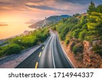 Aerial view of perfect mountain road and beautiful green forest at colorful sunset in summer. Dubrovnik, Croatia. Top view of road, sea, mountain, sky. Landscape with highway, sea coast, gold sunlight