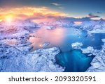 Aerial view of sea, snowy islands, mountains, road, blue sky at sunset in winter. Lofoten islands, Norway. Landscape with mountains and rocks in snow, reflection in water. Top view from drone. Nature