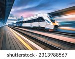 High speed train in motion on the railway station at sunset. Fast moving modern passenger train on railway platform. Railroad with motion blur effect. Commercial transportation. Concept. Travel