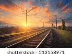 Railway station against beautiful sky at sunset. Industrial landscape with railroad, colorful blue sky with red clouds, sun, trees and green grass. Railway junction. Heavy industry. Evening in autumn