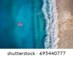 Aerial view of young woman swimming on the pink swim ring in the transparent turquoise sea in Oludeniz,Turkey. Summer seascape with girl, beautiful waves, azure water in sunny day. Top view from drone