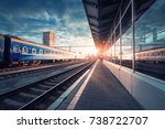 Beautiful train with blue wagons at the railway station at sunset. Industrial view with modern train, railroad, railway platform, buildings, sky with clouds in sunny evening. Railway tourism. Vintage