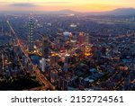 Aerial view of Taipei at dusk, the capital city of Taiwan, with 101 Tower standing out in Xinyi Commercial District, ovoid shaped Taipei Dome in nearby area and Tamsui River winding under golden sky