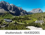 Aerial view of Pass Gardena on a sunny summer day with rugged Sella & Sassolungo mountains in background, highways & hiking tracks through the green grassy valley in Dolomiti, South Tyrol, Italy
