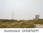 Lighthouse and bunker in the sand dunes on the beach of Blavand in fog, Jutland Denmark Europe