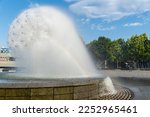 Spherical fountain spraying water in city park. Transparent splash in form ball. Fanshaped structure how dandelion blowball. Gush water and movement drops. Refreshing cool water on hot summer day.