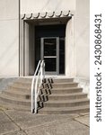 Small photo of Pittsburgh, PA USA. February 26,2024. Retro looking art deco entrance with front steps and metal gray railing in the center is seen on a sunny clear day in the Northside neighborhood of Pittsburgh.