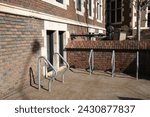 Small photo of Pittsburgh,PA USA. February 26, 2024. Bicycle parking area without any bicycles is seen in front of an old red brick building on the Northside of Pittsburgh.