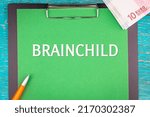 Small photo of BRAINCHILD - word (text) and a bundle of money, euro bills on a green background of a notebook, a pen and a wooden table. Business concept: buy, sell, commerce (copy space).