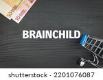 Small photo of BRAINCHILD - word (text) and euro money on a wooden background, trolley (basket) for goods. Business concept, buying goods and products (copy space).