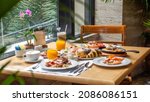 Small photo of Breakfast in luxury hotel. Table full of various food from buffet in modern resort. Morning food - fresh bakery, glasses of orange juice, eggs, cold cuts and plate with tropical fruits in restaurant