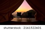 Small photo of Tourist tent in camp among with mountain view on sunrise. View from tent camping on amazing sunrise with mountains and two folding camping chair. Travel vacation on nature