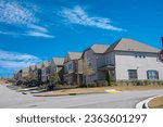 Small photo of Corner two story houses by large residential streets intersection in upscale neighborhood suburbs of Atlanta, Georgia, USA, new development homes under sunny blue cloud sky. Subdivision HOA area
