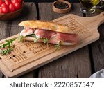 Small photo of Italian panini sandwich with mortadella or Parma ham, multi grain baguette arugula and onion. Takeaway food