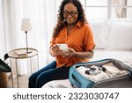Senior woman packing her luggage with all of the essentials for her upcoming trip, using the checklist on her phone to double-check her carry-on. Retired traveler embarking on a sightseeing journey.