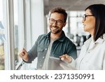 Small photo of Business man brainstorming with his colleague using sticky notes. Creative business people standing next to a window and discussing their ideas.