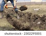 Small photo of Drainage ditch. A man is digging a ditch. Laying a drainage pipe. Earthwork. A Worker digs soil with shovel.