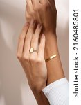 Small photo of Woman Jewelery concept. Womanâ€™s hands close up wearing rings and bracelet modern accessories elegant life style. Beige background