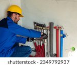 Small photo of Underfloor heating installation. Water floor heating system interior. Plumbing pipes in apartment during under renovation. Underfloor heating manifold. Worker attache the tube to the collector heating
