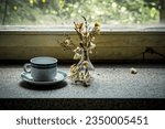 Small photo of a morbid window stick with coffee cup and wilted flowers in a lost place