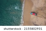 Small photo of Drone photography. We see how the sea collides with the stones and golden sand of a beach in Mexico leaving rest of white foam. we can see a boat coming in to the water with a red roof.