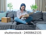 Young woman unpacking online purchase box with new smartphone