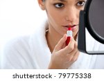 Woman applying lipstick in front of mirror