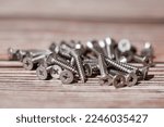 Small photo of Tapping screws made of steel on wood background, metal screw, iron screw, chrome screw, screws as a background, wood screw, concept industry. copy space for text.