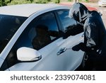 Small photo of Close-up car thief hand holding screwdriver tamper yank and glove black. Man robber checking breaking entering alarm in a car stealing
