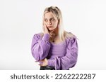 Small photo of Portrait of young blonde woman wearing ribbed blouse standing isolated over white background Lean head on palm hand and looks very thoughtful. Doesn't know what to do and in a predicament.
