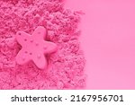 Small photo of Pink kinetic sand with starfish sand figure on light pink paper background with copy space. Early sensory education for children. Kids development concept. Leisure time on vacation. Place for text.