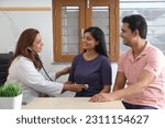 Small photo of Happy Indian couple getting checkup by gynecologist to make sure that mother is expecting baby. Young woman patient with husband getting checked up by senior gynecologist during consultation. Smiles