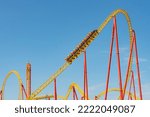 Yellow and red roller coaster with upturning trolleys on a turn and a loop