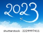 Happy New year 2023 concept travel on the blue background below cloudscape. Drawing by passenger airplane vapor steam contrail in sky