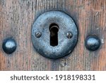 Old forged keyhole on a rustic wooden door. Metal lock.