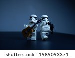 Small photo of Tangsel, Indonesia - May 27, 2021: firstorder trooper have duo performance, play accoustic guitar and sing in lowkey shadow mode photo. lego minifigs are made by the LEGO