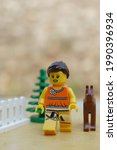 Small photo of Tangsel, Indonesia - September 18, 2020: potrait photo of lego girl minifigure in orange shirt have good walk with her brown dog outside. lego minifigs are made by the lego group.