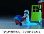 Small photo of Tangsel, Indonesia - May 27, 2021: lego first order trooper came out from the red house and bring the blue cube with red trolley. lego minifigs are made by the lego group