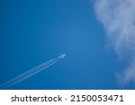diagonal lower left to upper right high altitude contrails from a four engine KLM Boeing 747-400 Cargo Jumbo jet aircraft entering cloud blue sky