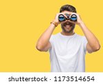 Young handsome man looking through binoculars over isolated background with a happy face standing and smiling with a confident smile showing teeth