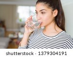 Beautiful young woman drinking a fresh glass of water at home
